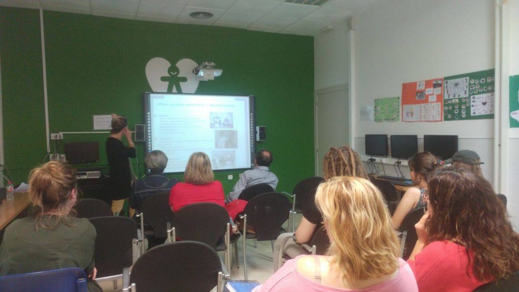 Imagen de profesionales, voluntariado y familiares de socias/os de Bona Gent atendiendo durante la charla